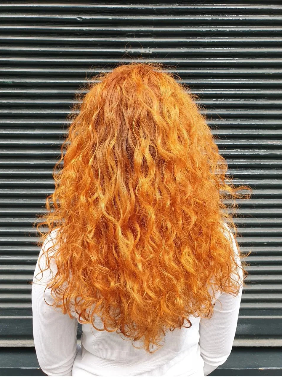 Balayage cuivré intense sur boucles longues, vue de dos — précision backstage appliquée en salon par Élodie Hue, Paris 3e